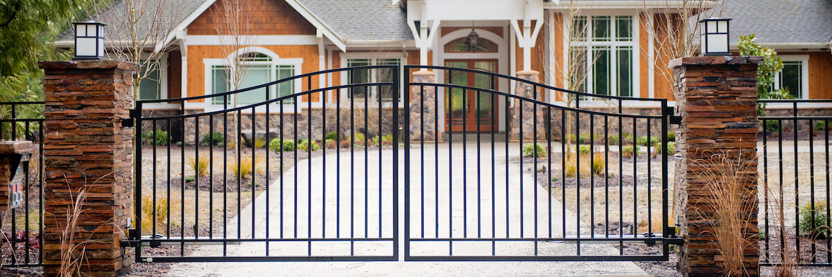 Custom Residential Driveway Gate With Stacked Stone Pillars And Automatic Swing Movements