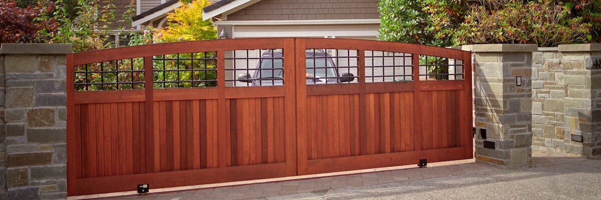 Custom Residential Wood Driveway Gate With Stone Pillars And Automatic Slide Movement