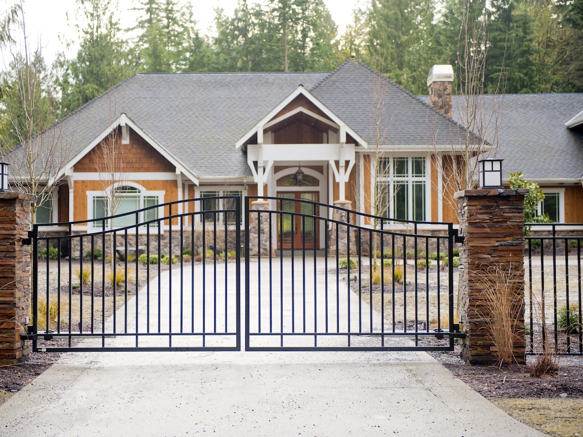 Custom Residential Driveway Gate With Stacked Stone Pillars And Flattop Fencing